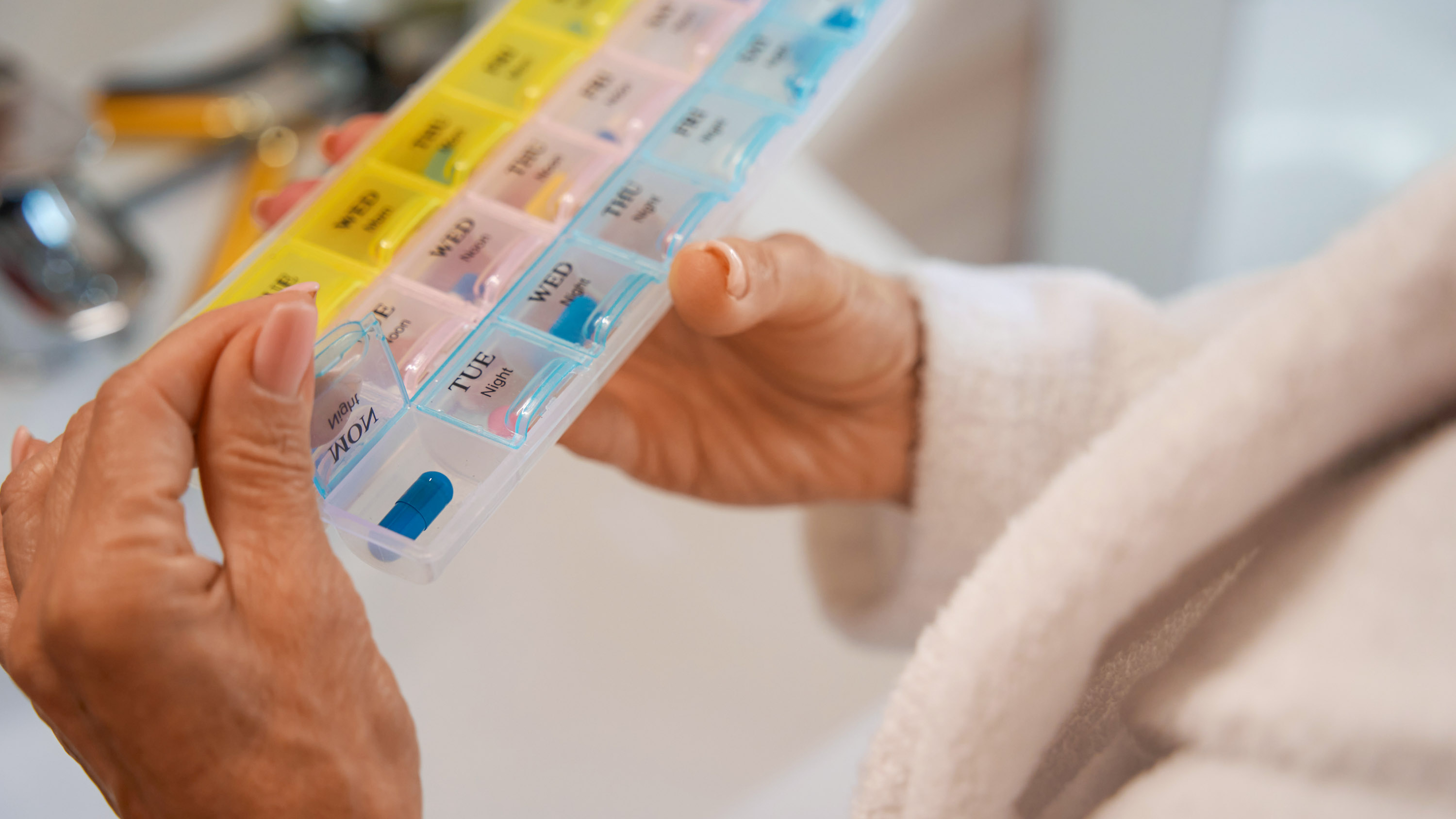 Woman holds a pill box with multi-colored cells in her hands