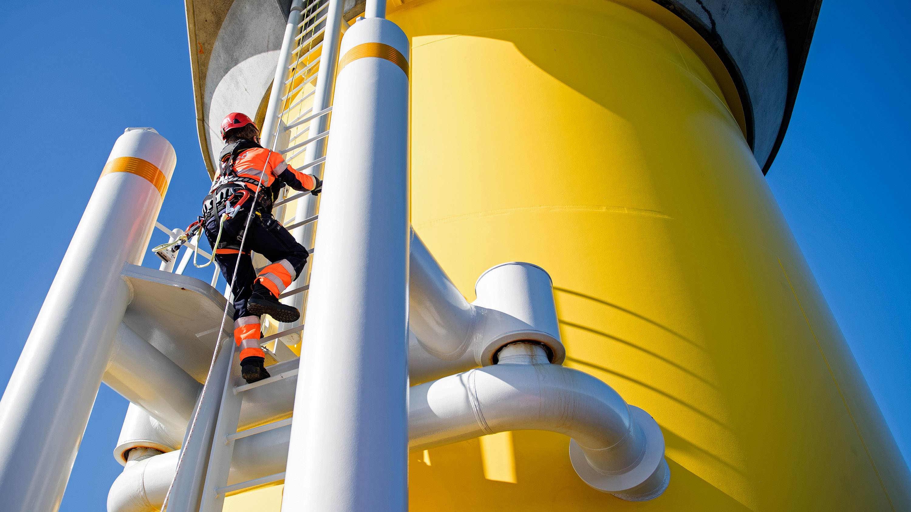 a worker climbs a turbine at the Offshore Windfarm Walney